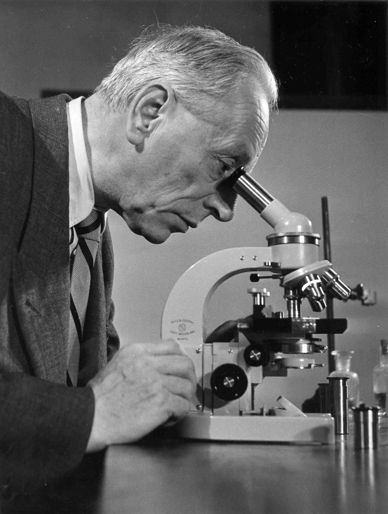 Een man kijkt door een microscoop